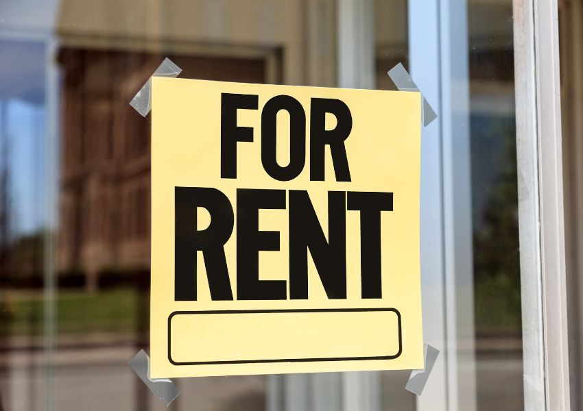yellow sign in the window with the words for rent written in bold black color